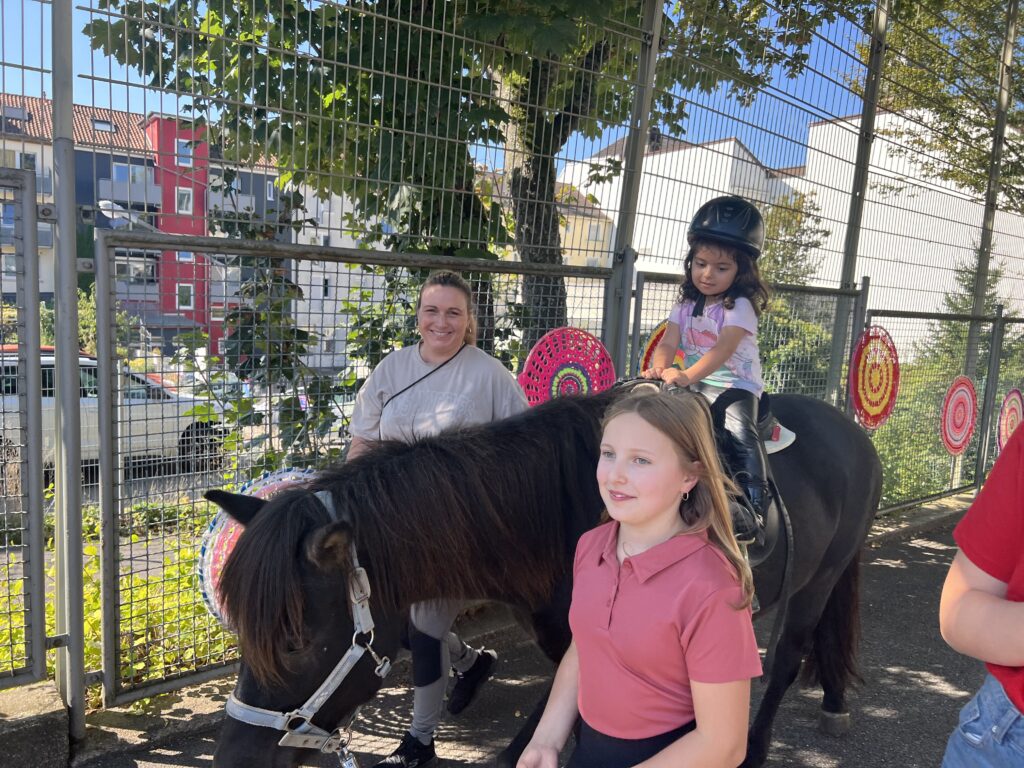 Mama Christine Brück und Tochter Lotte führen die Kinder auf den Ponys durch den Schulhof. Foto: Müller