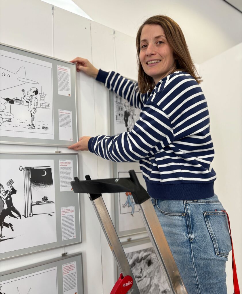 Die Museumspädagogin Anna Wölfling hängt ein Exponat der Karikaturenausstellung im Forum Alte Post